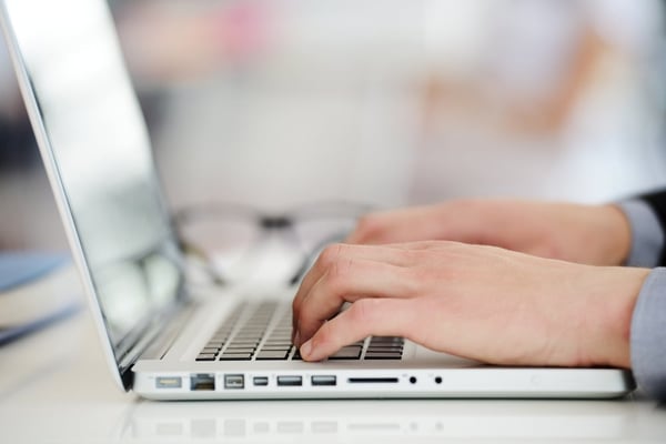 Two hands typing on a laptop.