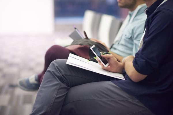 An adult learner in class holding a phone and notebook