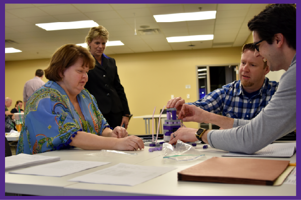 Team of three seated and working together on a strategic brick-building activity.